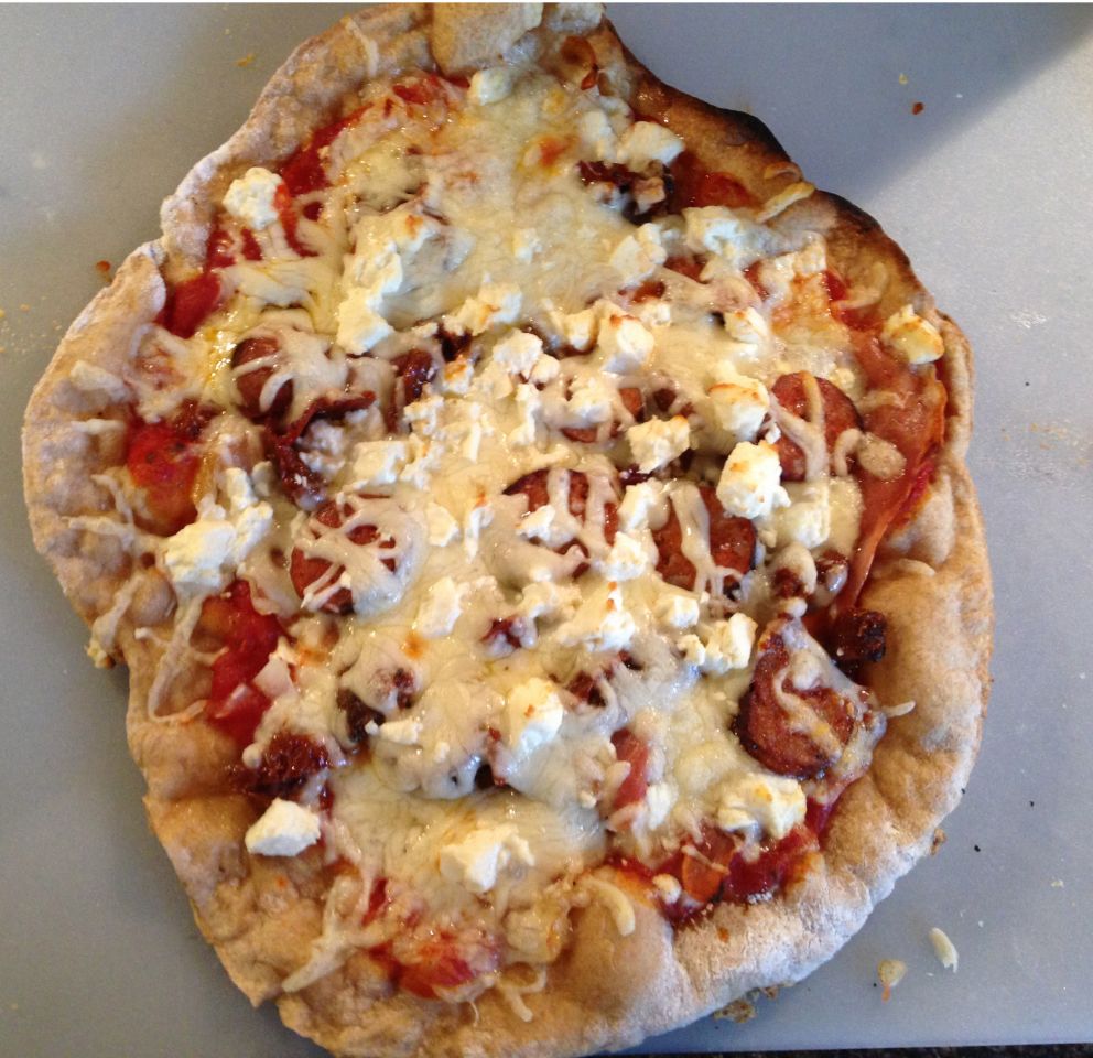 Pizza förberedd för att bakas på pizzasten
