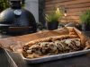 Loaded steak sandwich with onions, peppers and melted cheese on a toasted roll, served on parchment.